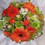 Vibrant Orange Gerbera Daisies, 
Mini Green Cymbidium Orchids, Lime Green Kermit Mums, Orange Dahlias, Orange Spray Roses, 
and Star of Jerusalem. 